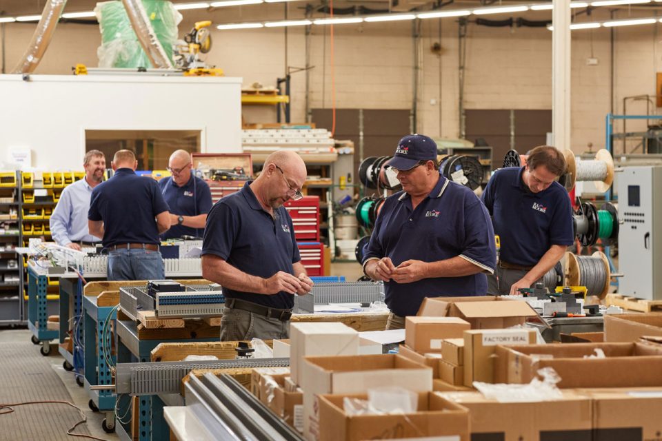 Employees of R.A. Moore review system integration equipment in the warehouse