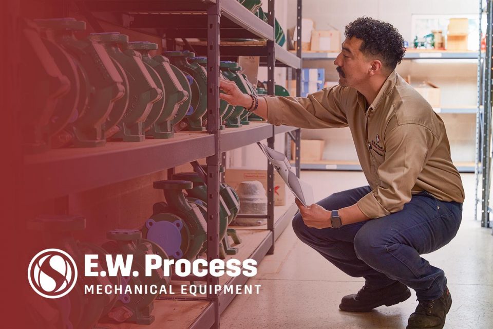Male employee of E.W. Process looking at industrial pumps on a shelf