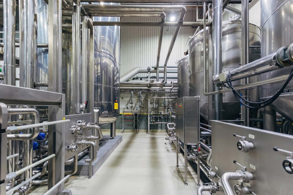 Giant silver vats and piping in beverage processing plant