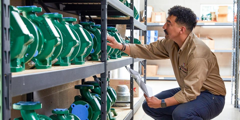 Male employee of E.W. Process looking at industrial pumps on a shelf