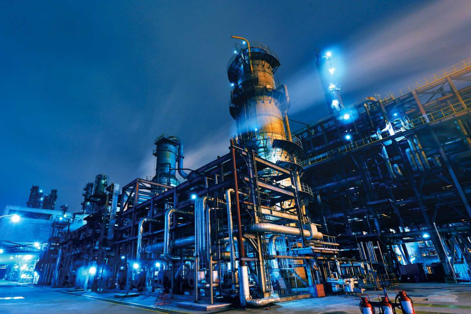 exterior of an industrial factory at dark with blue lights and fog