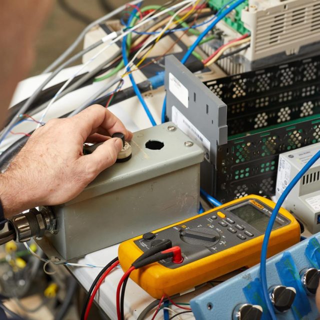 R.A. Moore employee using a multimeter to test system integration equipment