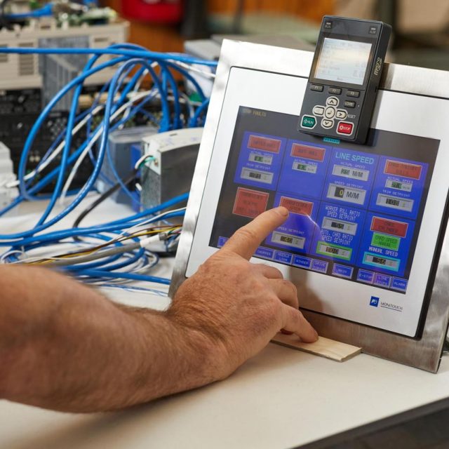 A hand with extending index finger about to select an item from the touch screen of a process control unit