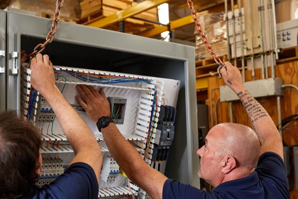 Two employees of R.A. Moore work to install a control panel for system integration
