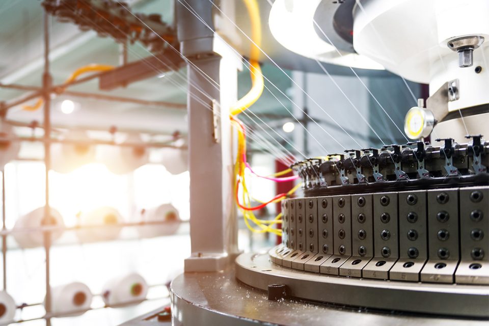 textile threading machine with large spools of thread in the background